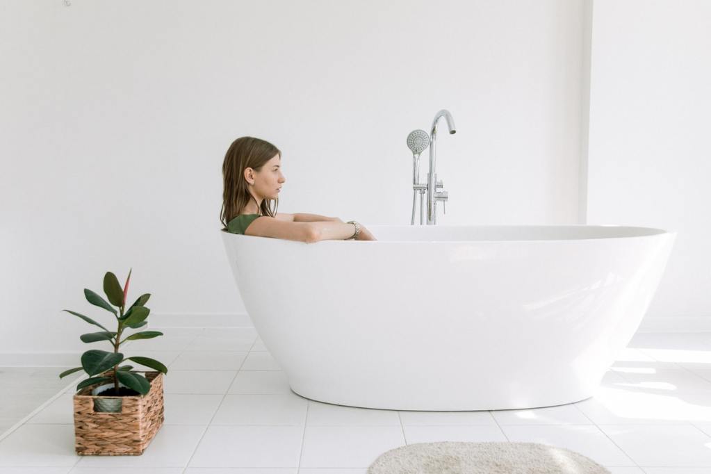 Woman in a tub next to a plant