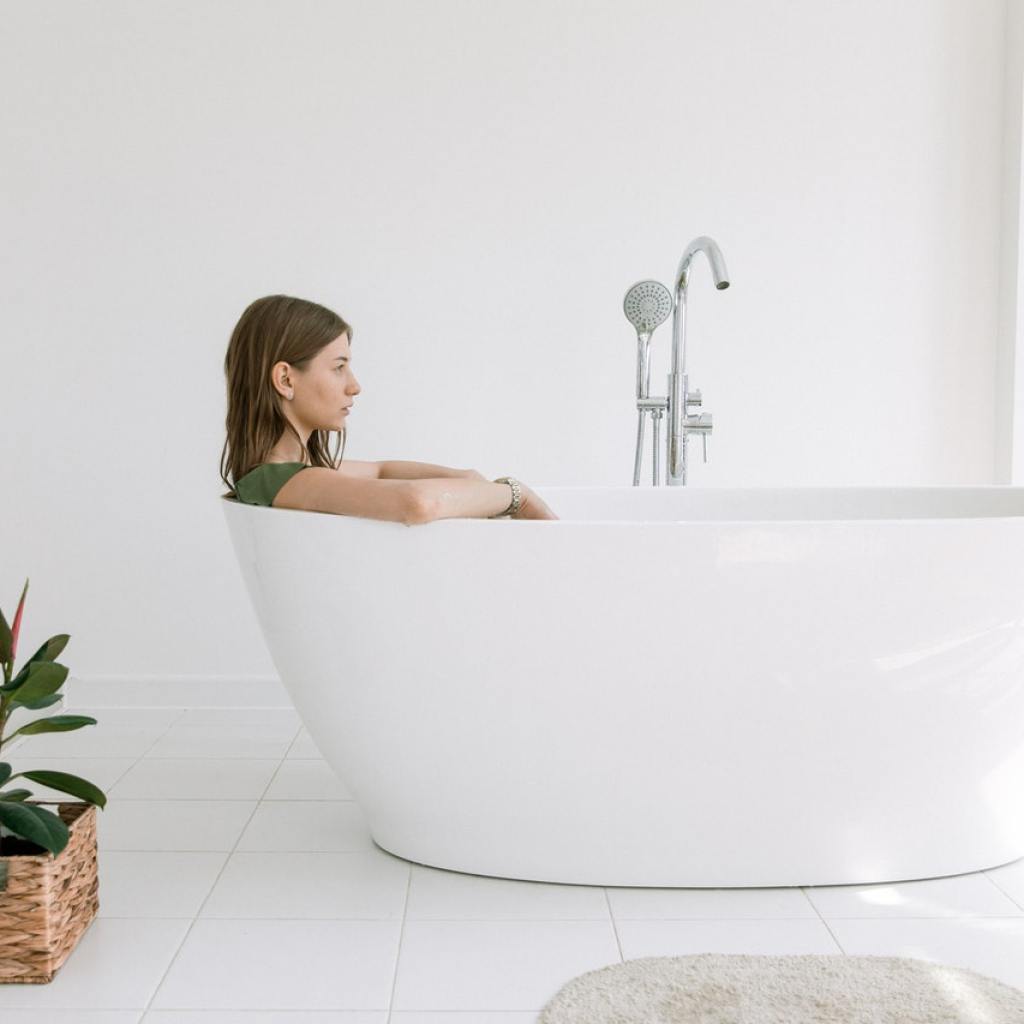 Woman in a tub next to a plant