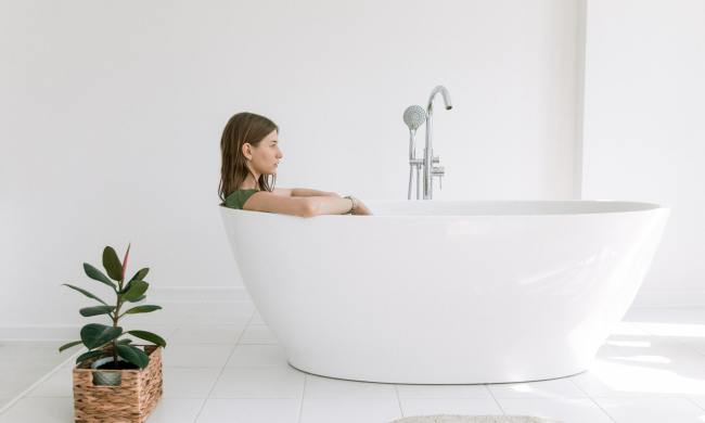 Woman in a tub next to a plant