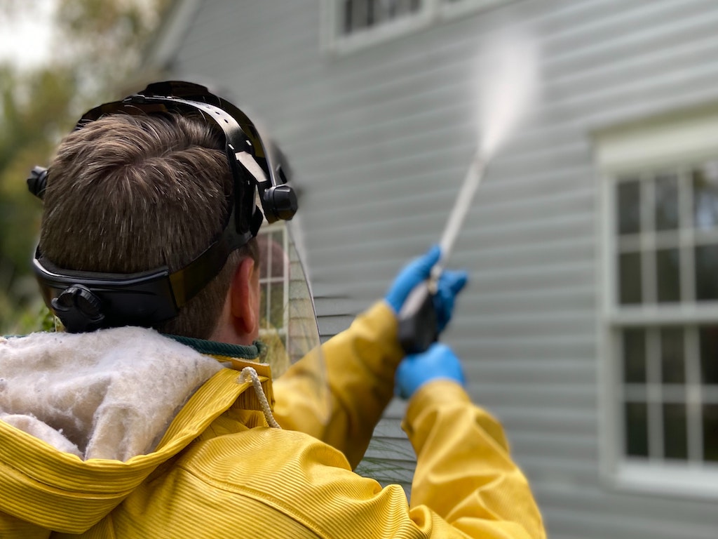 man pressure washing home