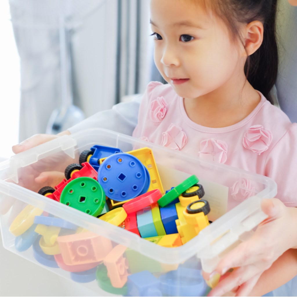 Small child holding box of toys