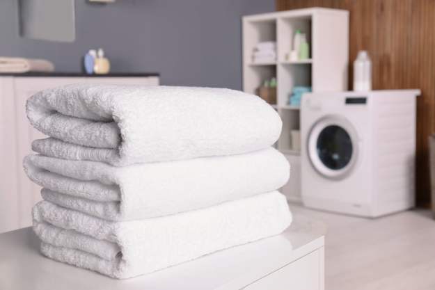 Three white towels folded in a modern laundry room