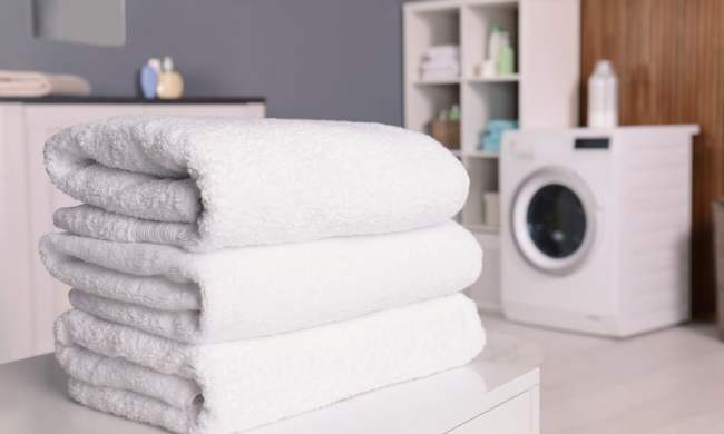 Three white towels folded in a modern laundry room