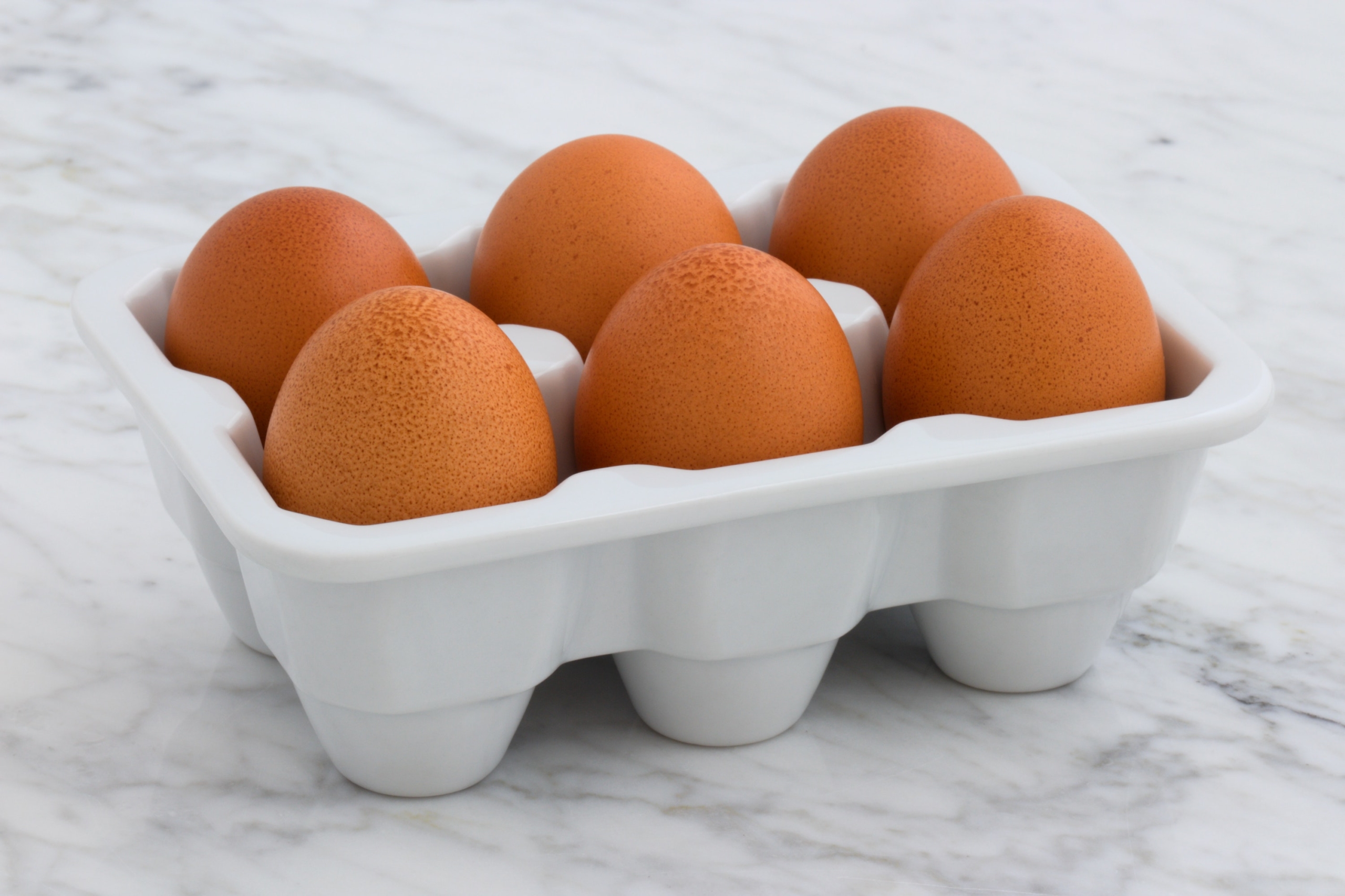 Hard-boiled eggs in a carton atop a marble counter