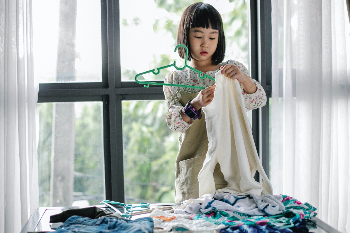 young girl hanging dress with a pile of laundry