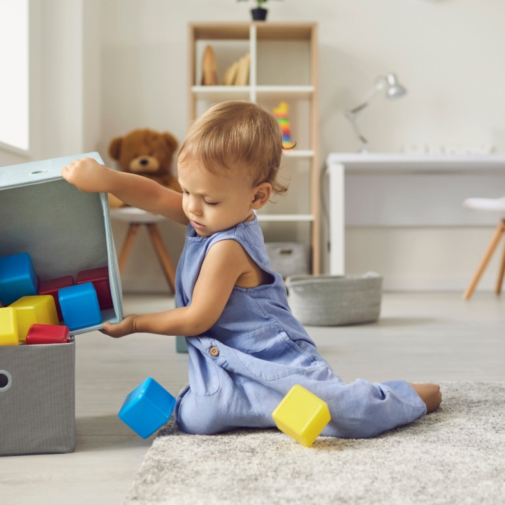 young child helping to clean up in playroom