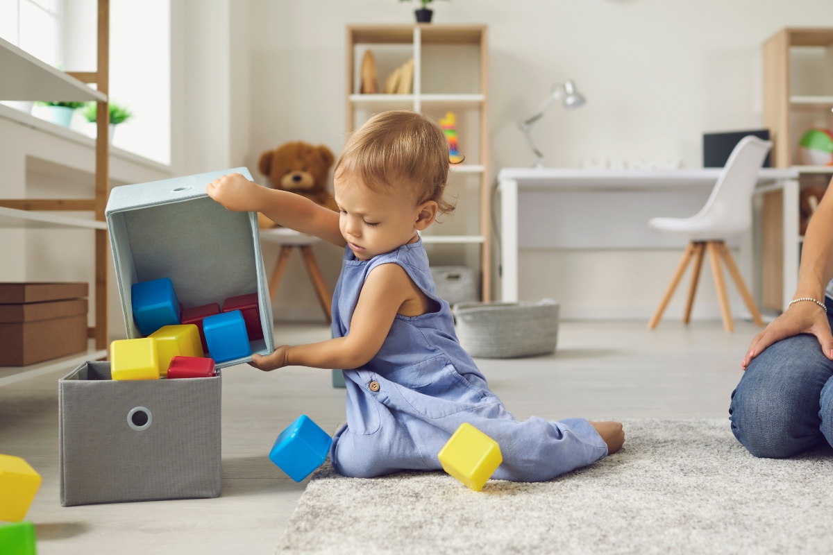 young child helping to clean up in playroom