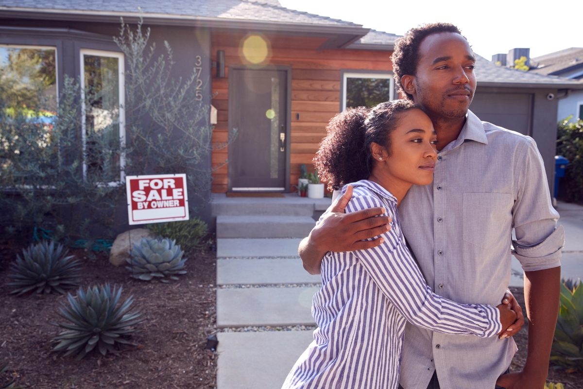 couple standing in front of home for sale