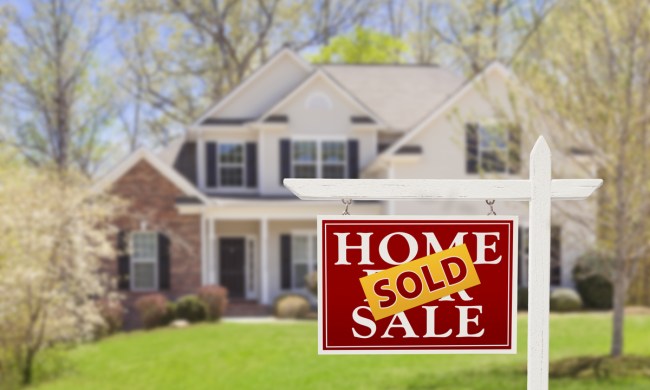 For sale home sign in front of house that says "sold"