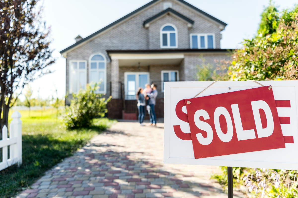 family in front of home with sold sign in yard