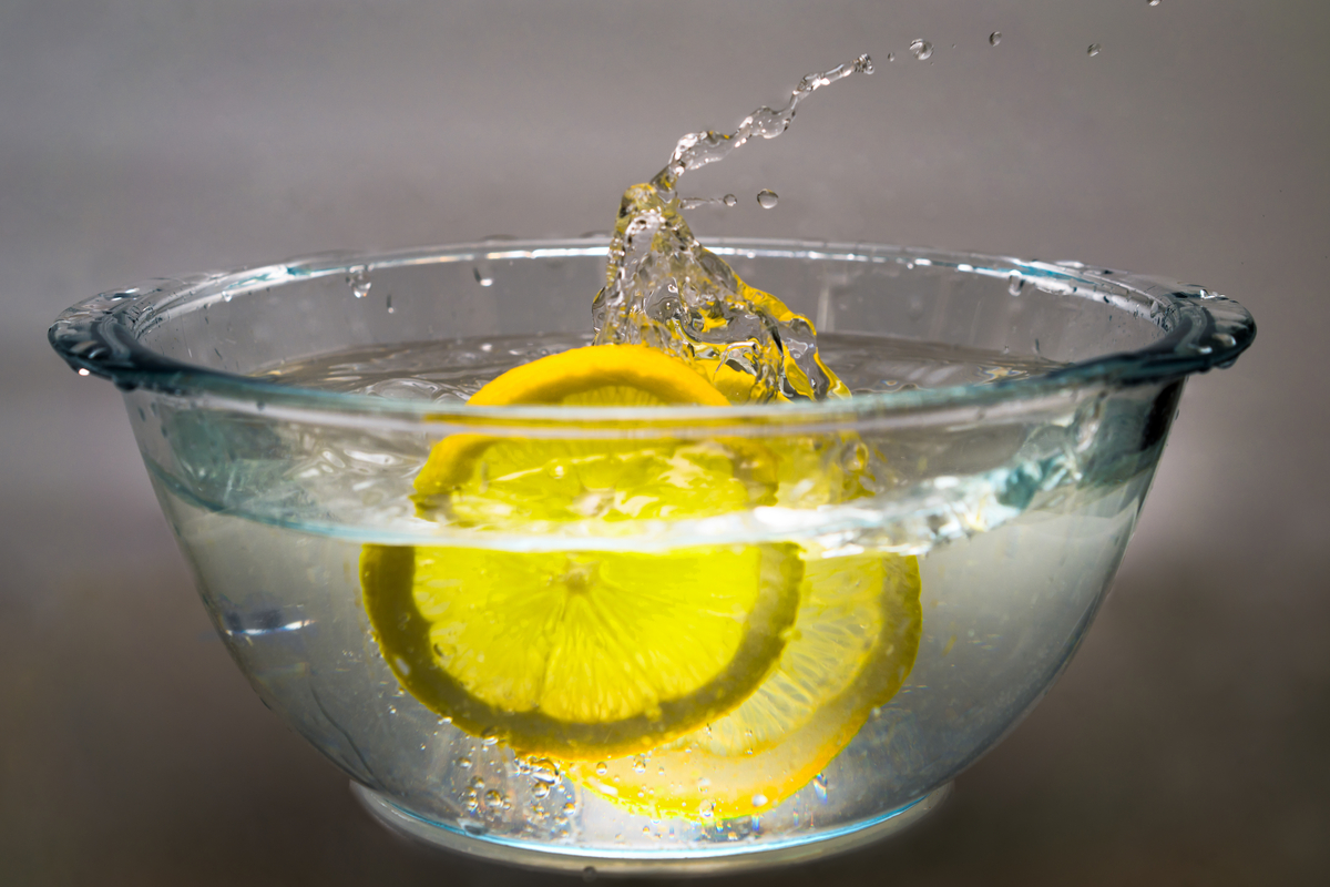 Lemon slices splashing in a glass bowl of water