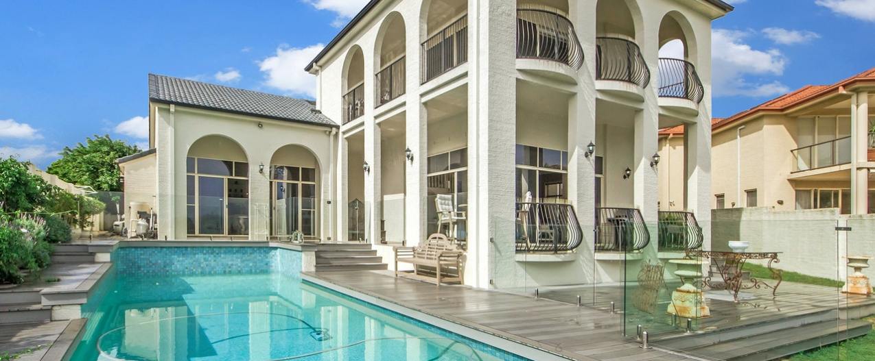 Outdoor inground pool with white two story home