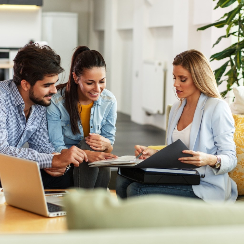 Real estate agent talking with homeowners with laptop on the table