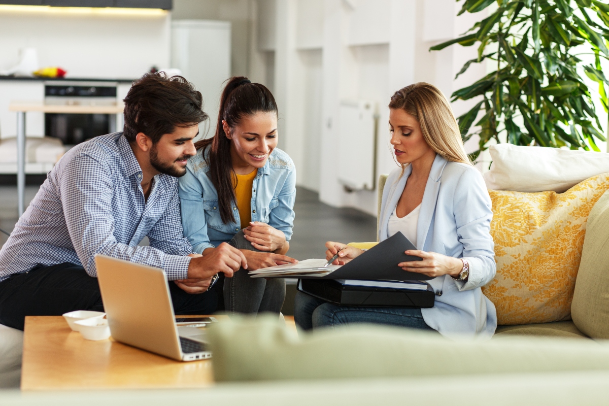 Real estate agent talking with homeowners with laptop on the table