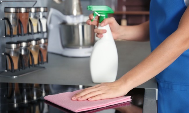 woman with a spray bottle cleaning the stovetop
