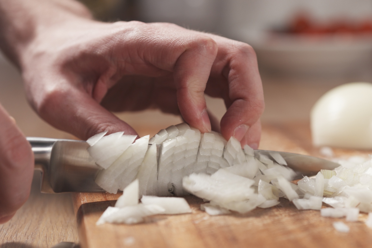 man dicing an onion on a cutting board