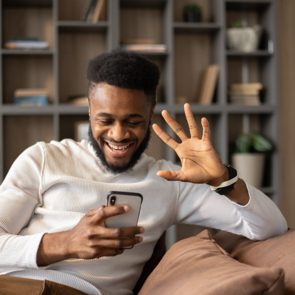 man waving at his phone camera during virtual call