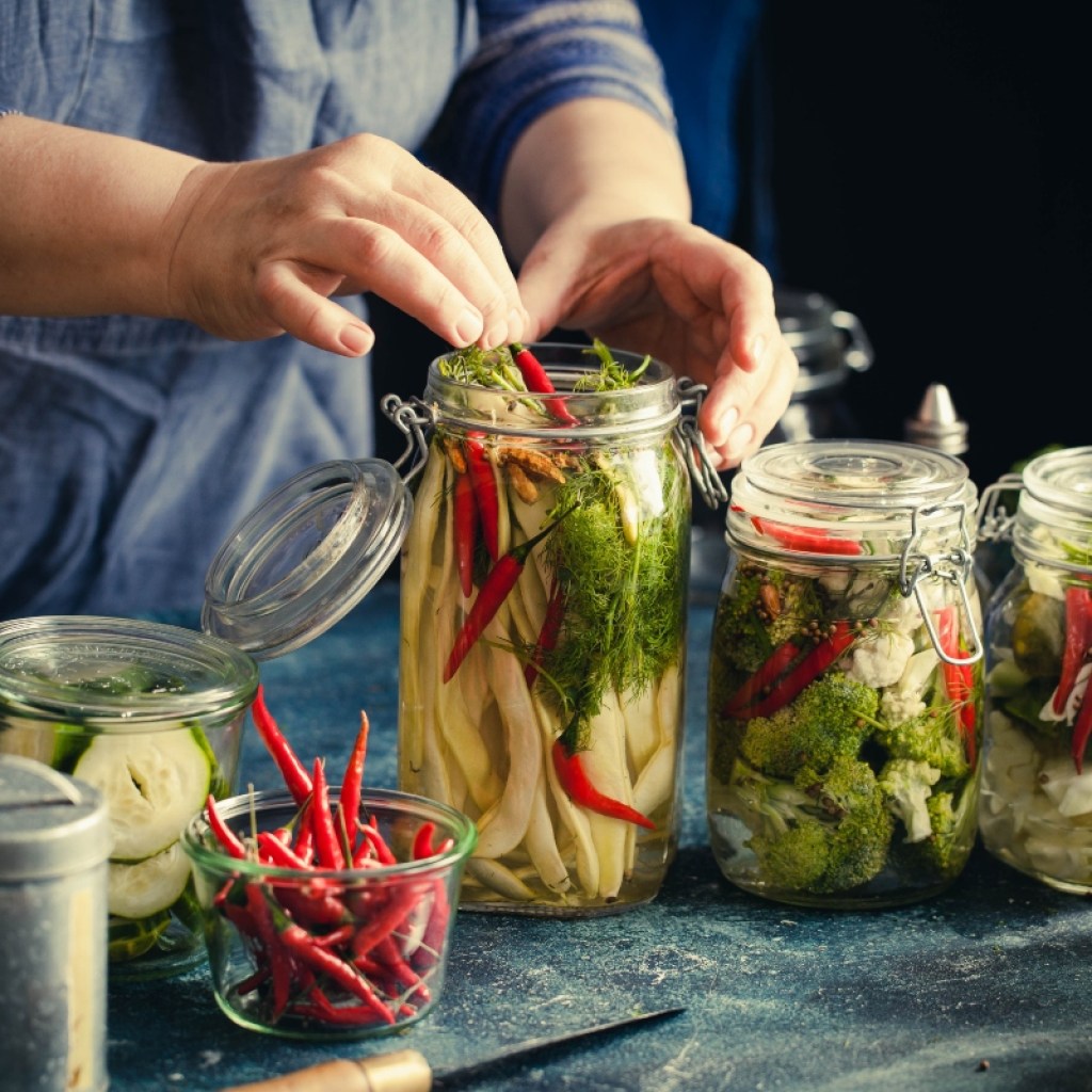 person canning chilis and vegetables