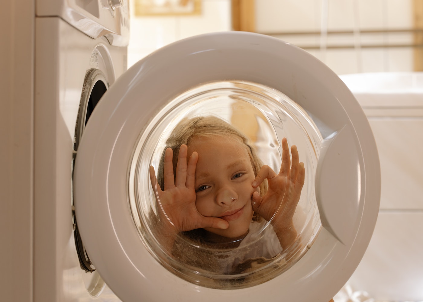 A little kid peaking behind the washer door.