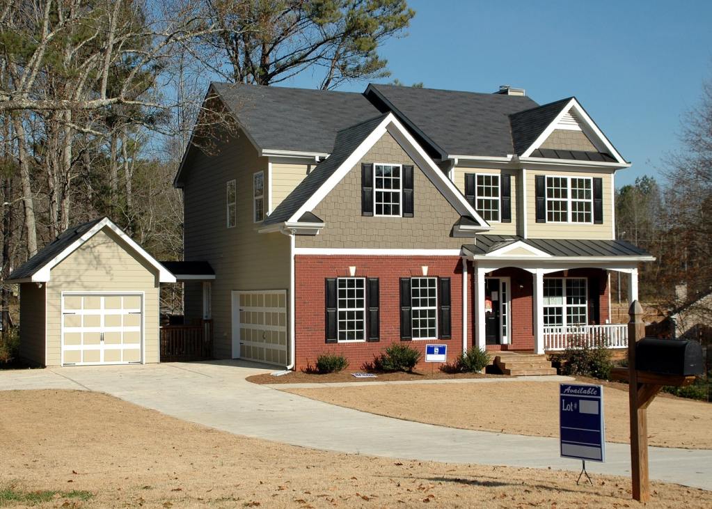 A house with a sale sign in the yard and a curved driveway