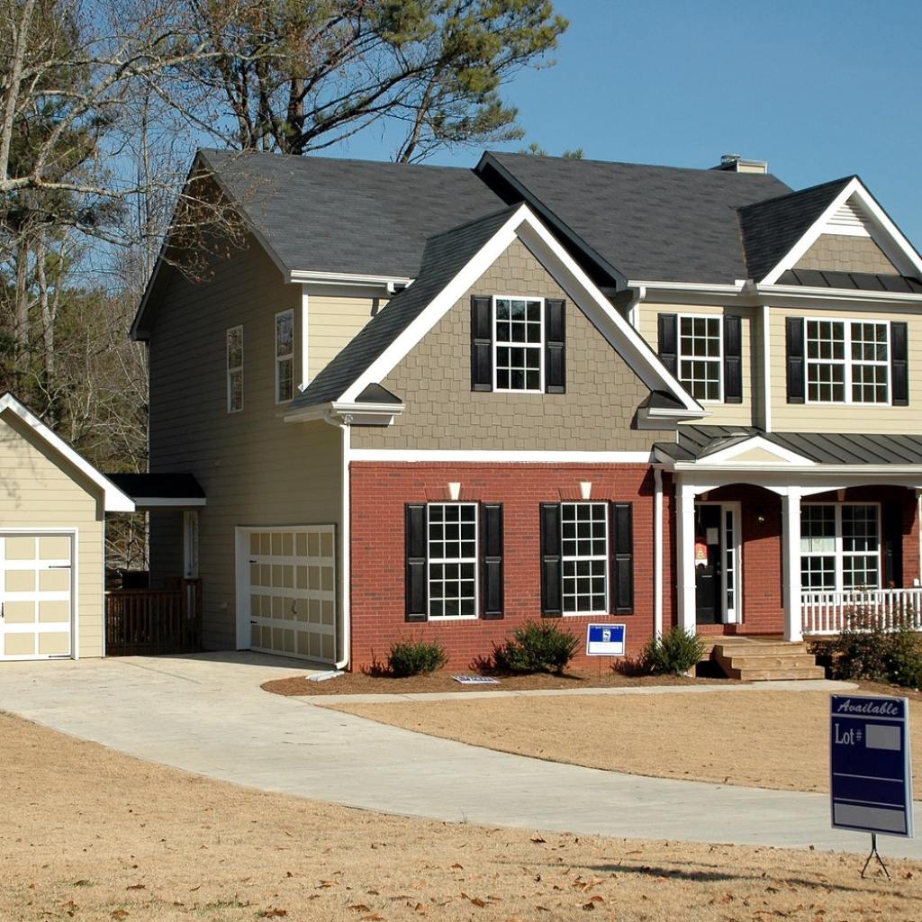A house with a sale sign in the yard and a curved driveway