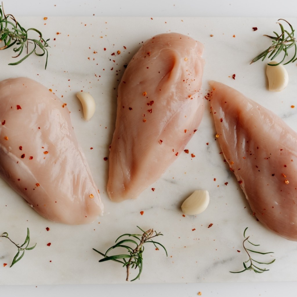 raw chicken breast on cutting board with spices