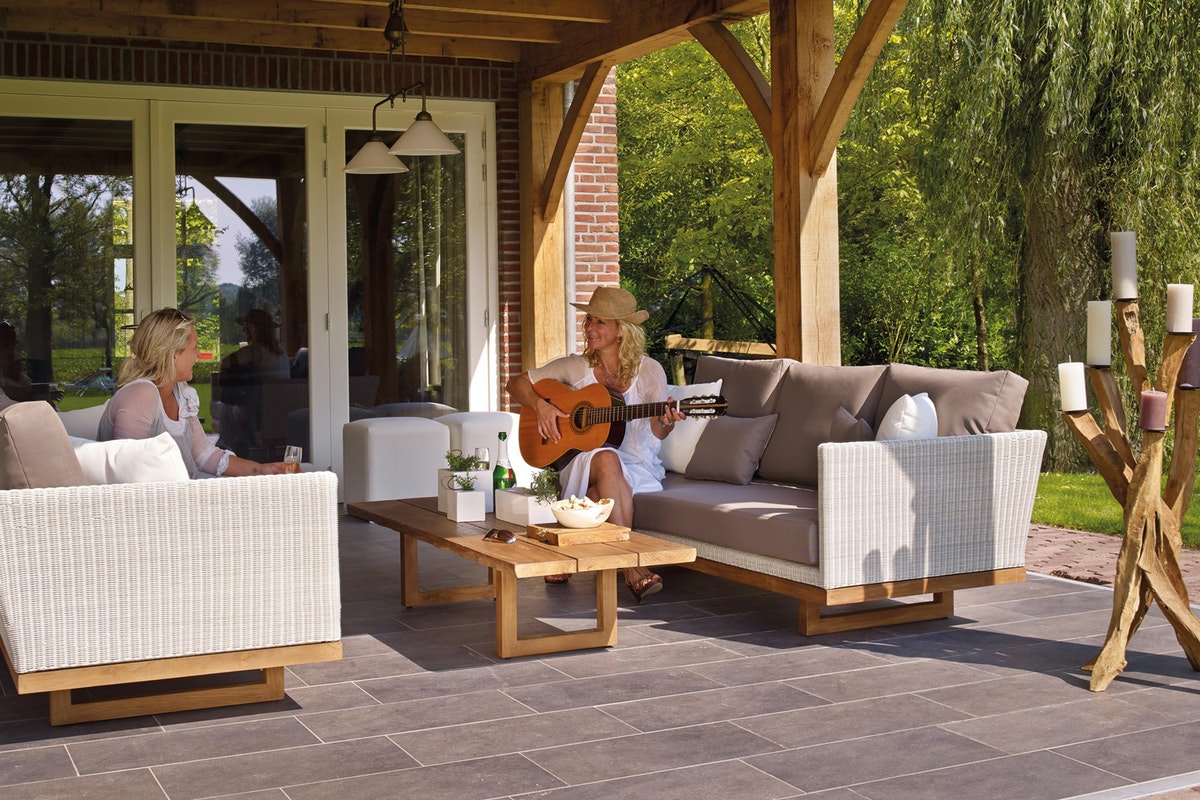 Two women on the patio with one playing the guitar