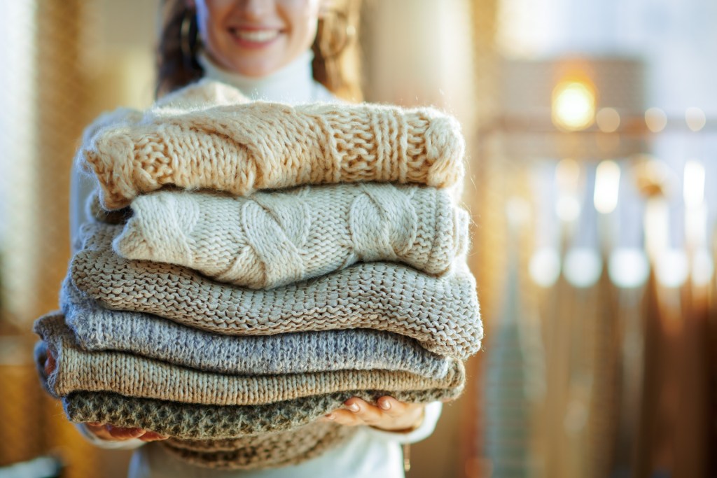 woman carrying folded winter sweaters