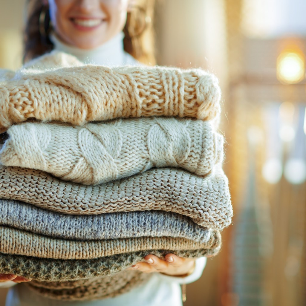 woman carrying folded winter sweaters