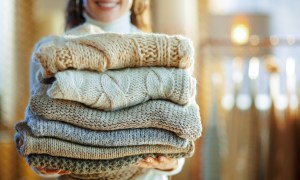 woman carrying folded winter sweaters