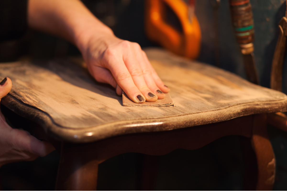 Close-up of a hand sanding a chair seat