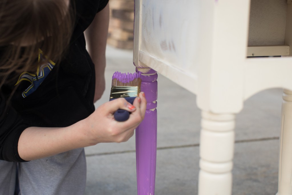 closeup of a woman's hand painting a table leg