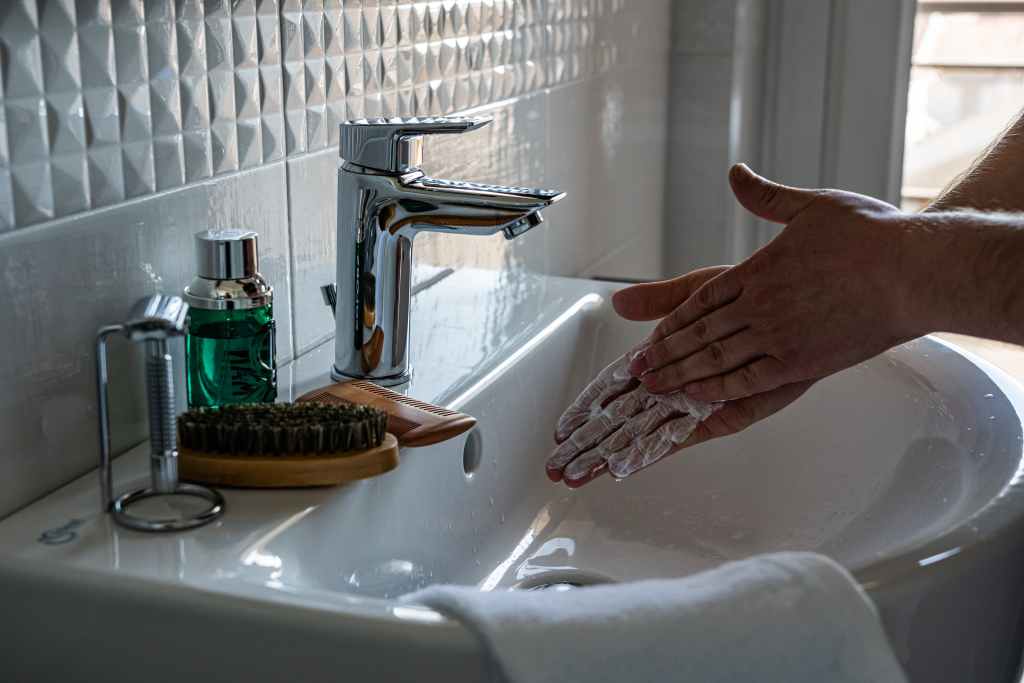 person washing hands in bathroom sink