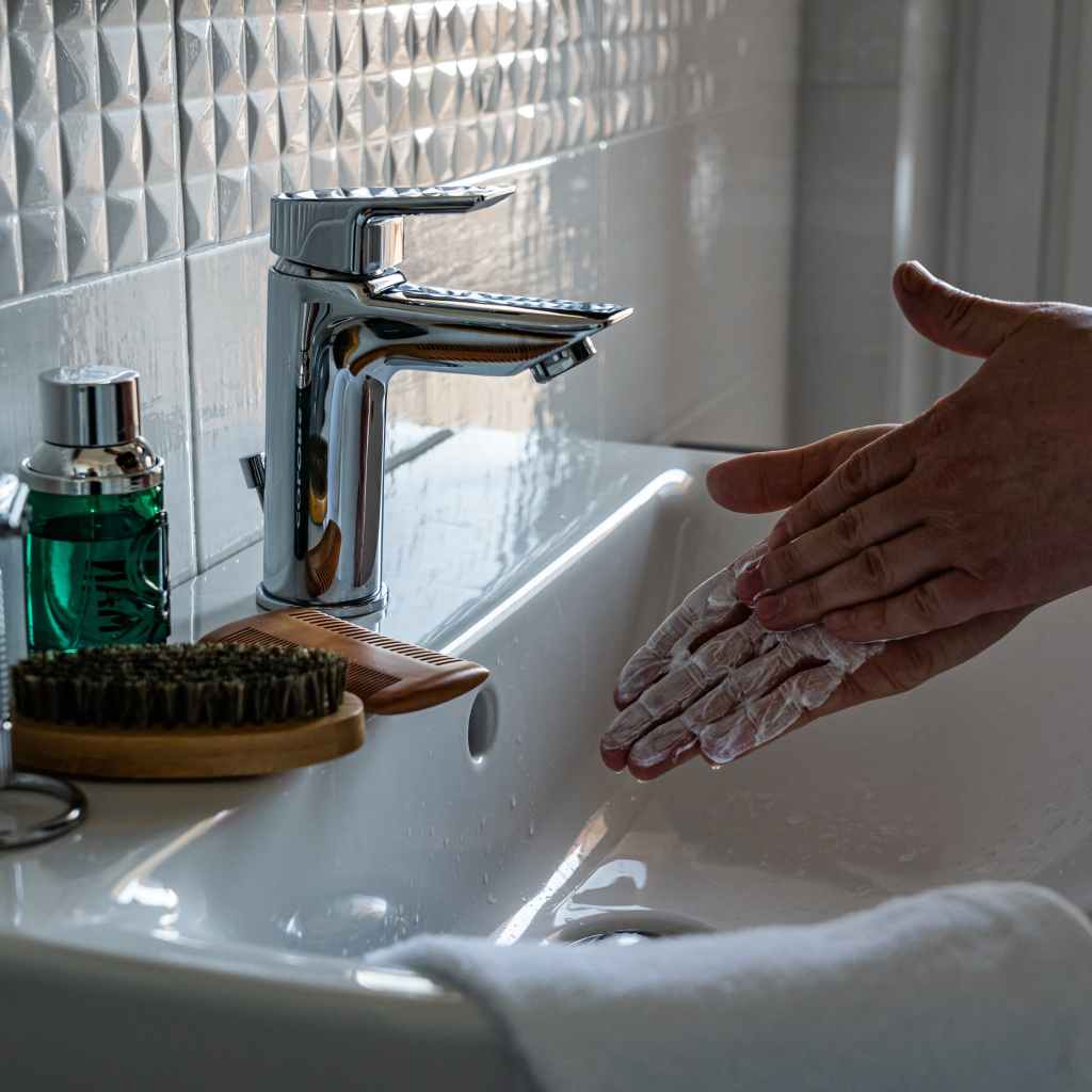 person washing hands in bathroom sink