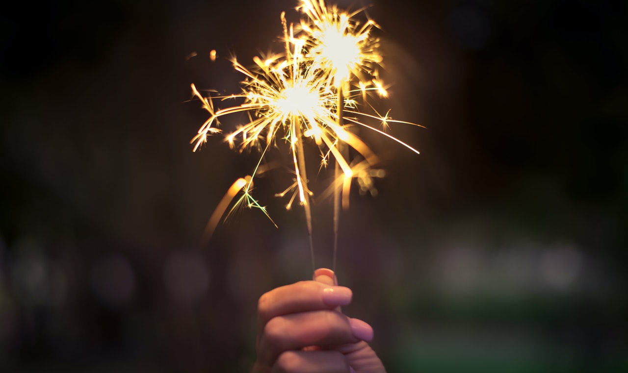 A hand holding a sparkler at night