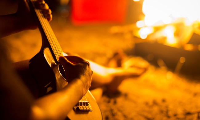 playing ukulele beside a campfire
