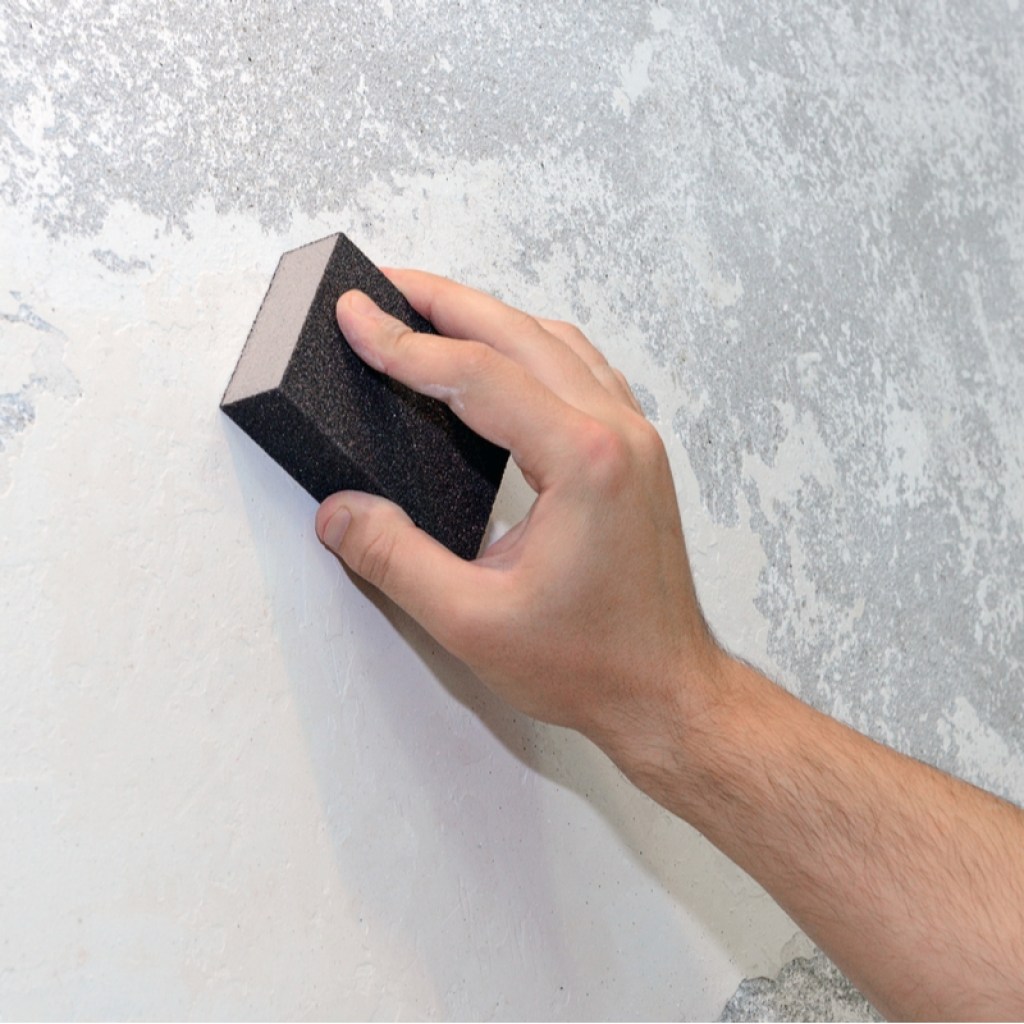 Person sanding down uneven walls