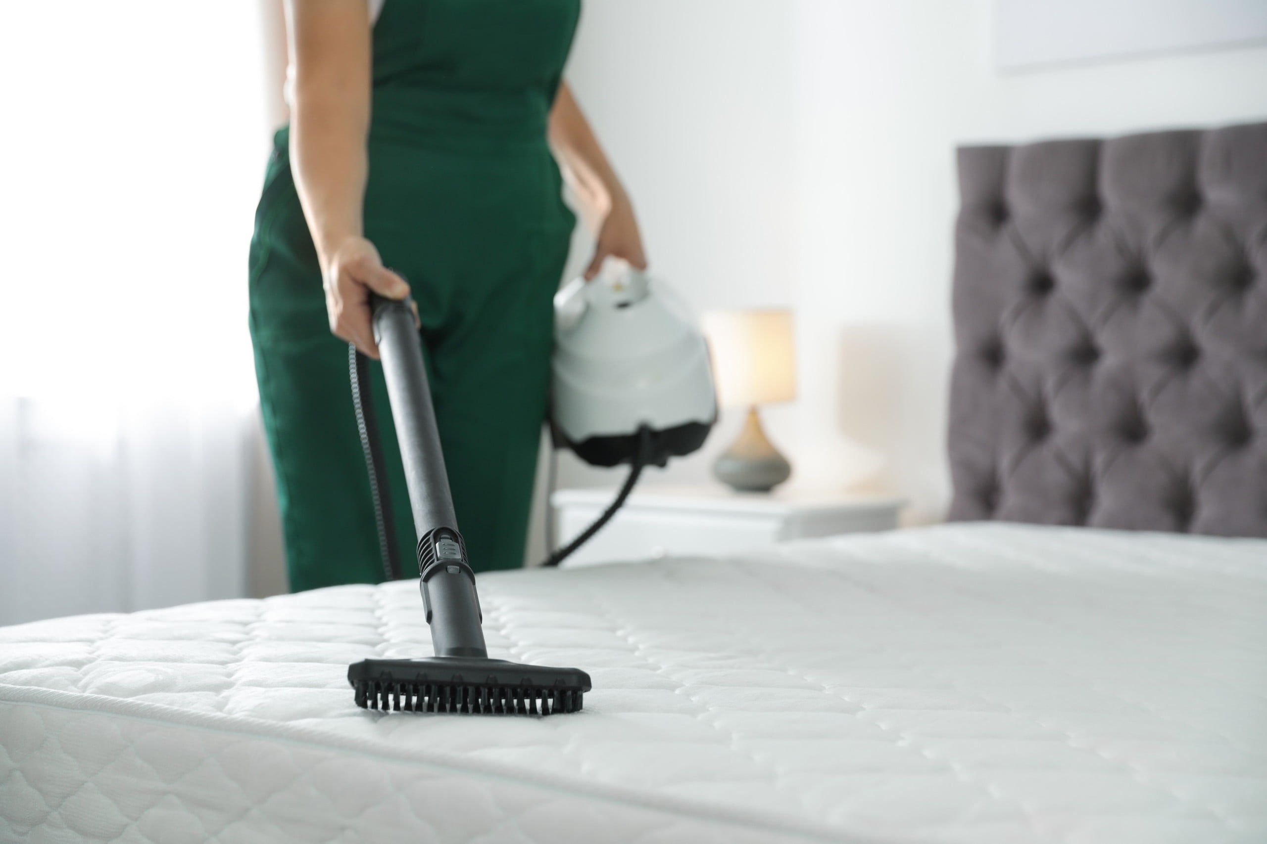 Woman vacuuming mattress with brush attachment