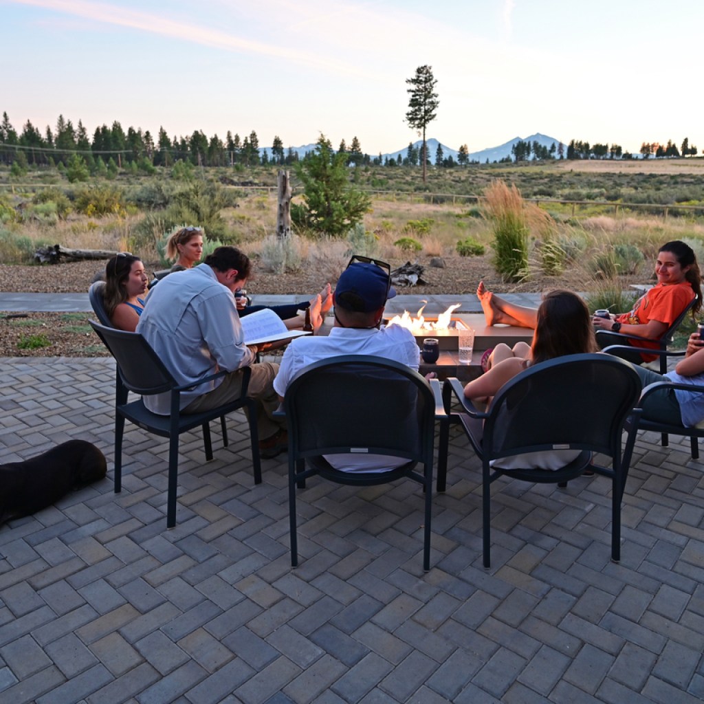 six friends sitting around a fire pit in the evening