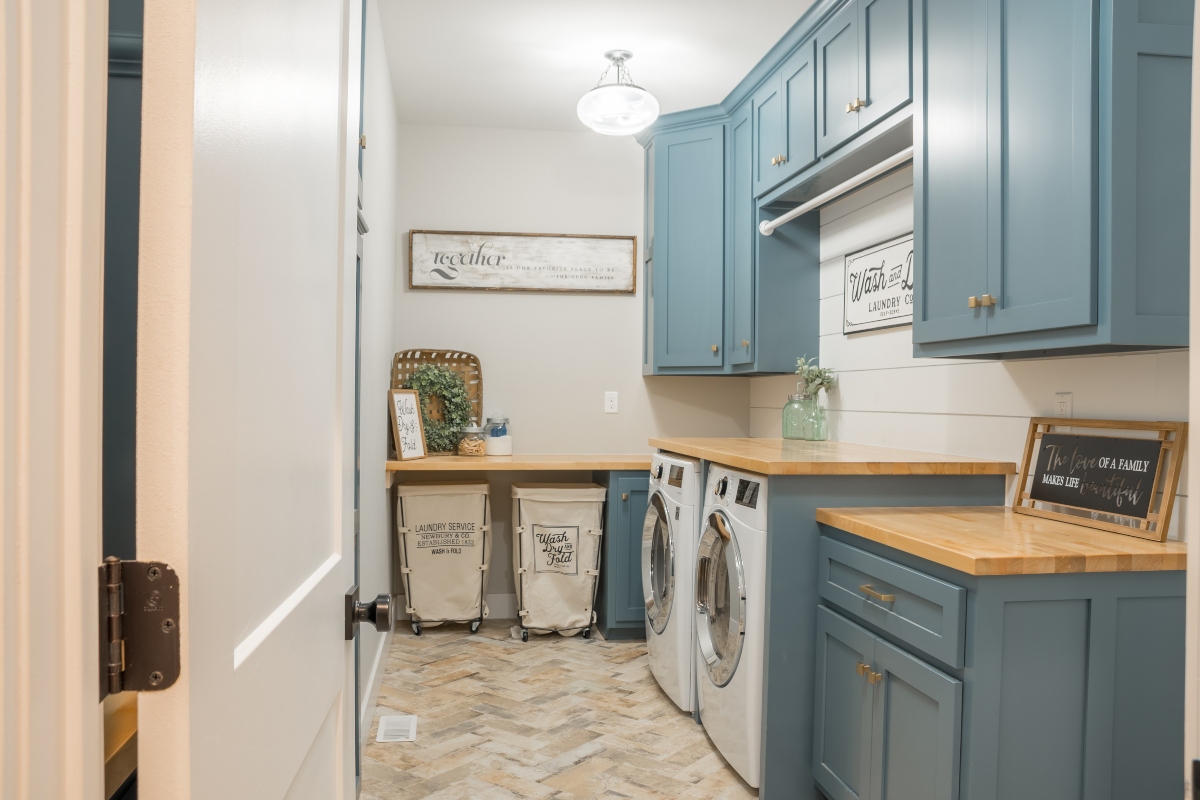 Well lit laundry room with blue cabinets