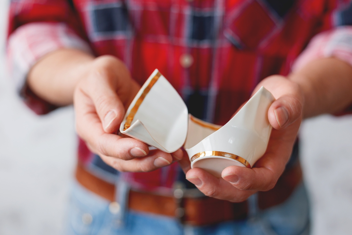man in plaid shirt holding broken mug