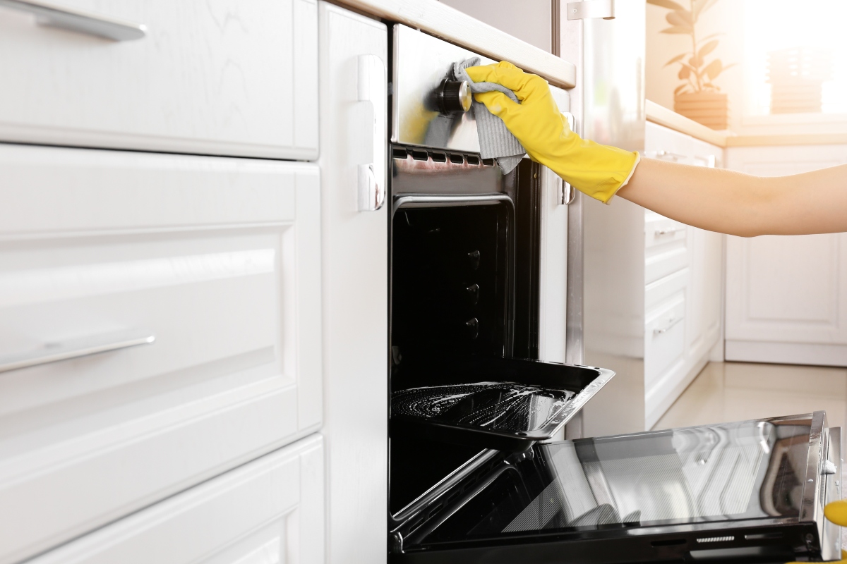 Gloved hand cleaning an oven
