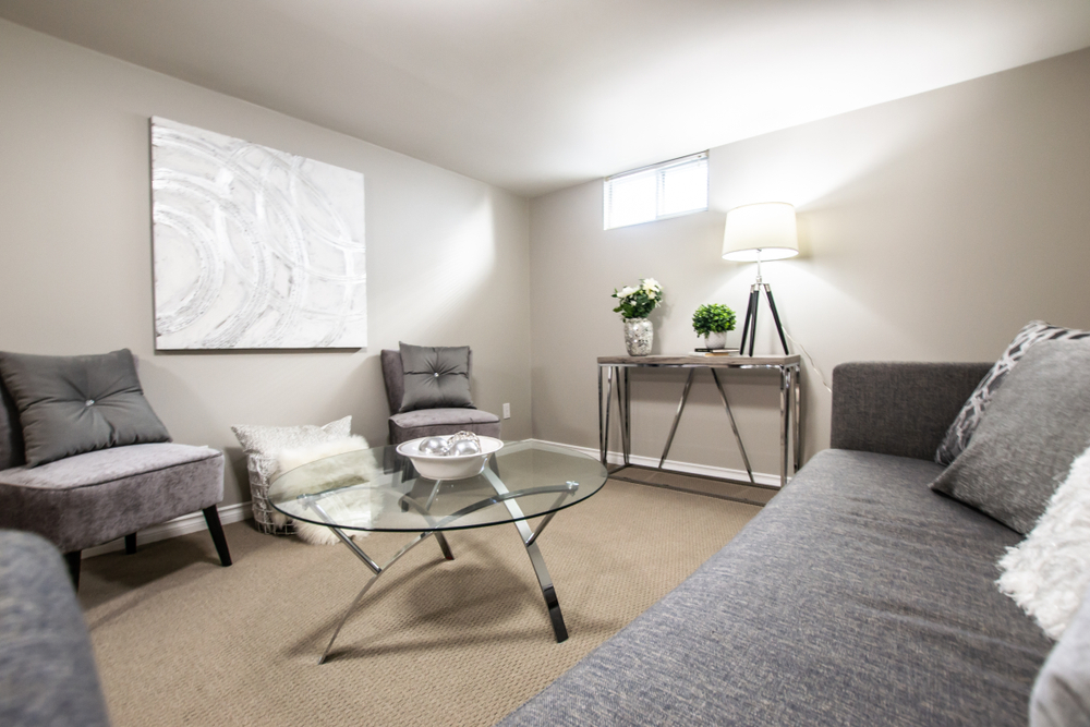 Finished basement with gray furniture and white walls