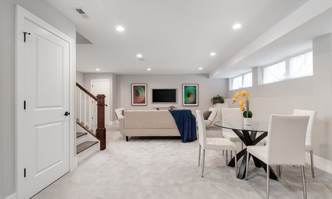 Finished basement seating area with white walls and carpet