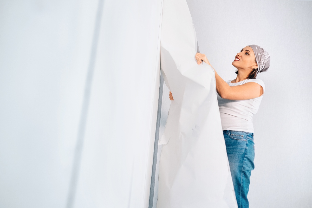 woman removing wallpaper from the wall