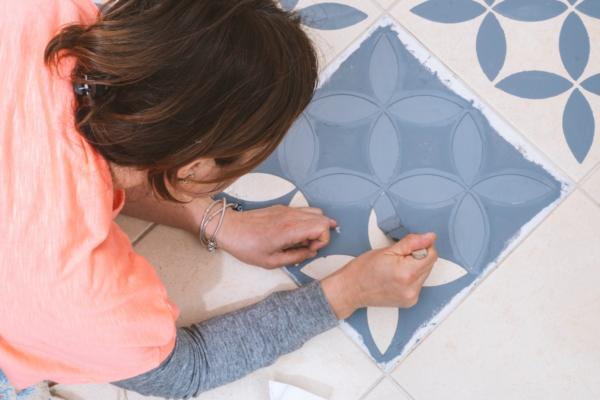 woman painting bathroom floor with a stencil