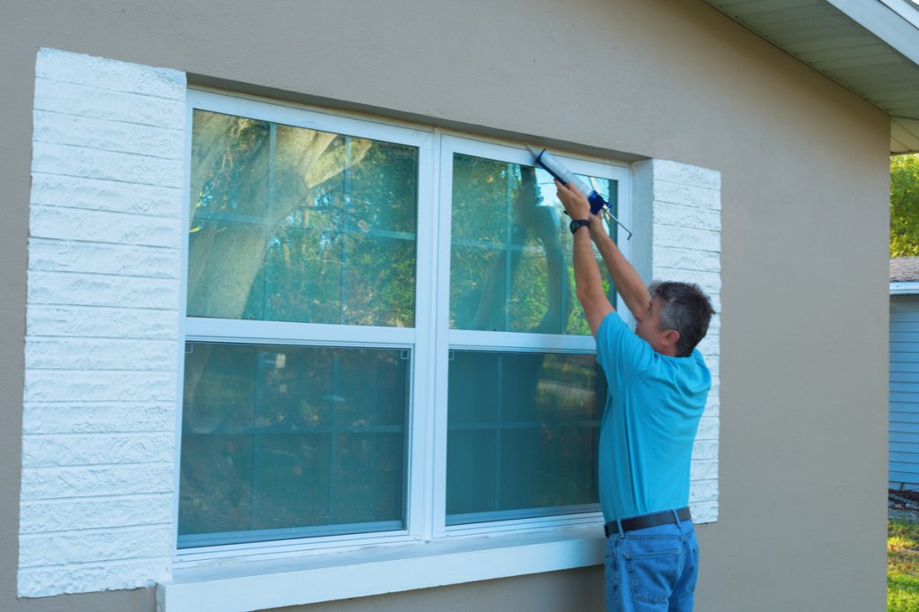 Man caulking around window