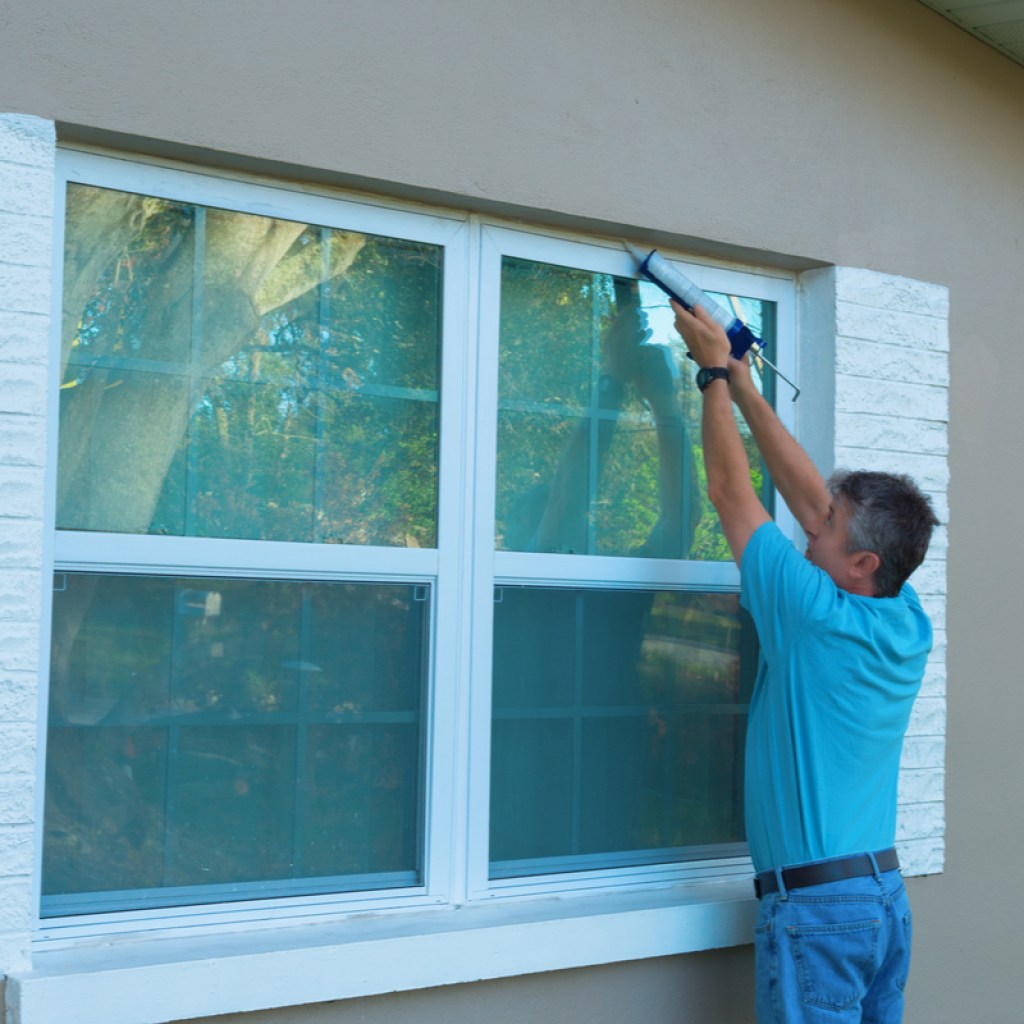 Man caulking around window