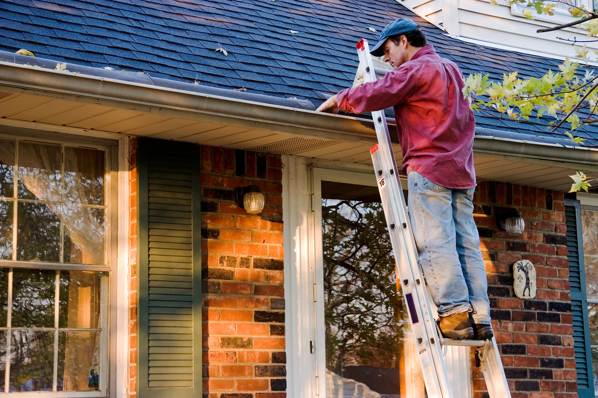 man on a ladder cleaning rain gutters