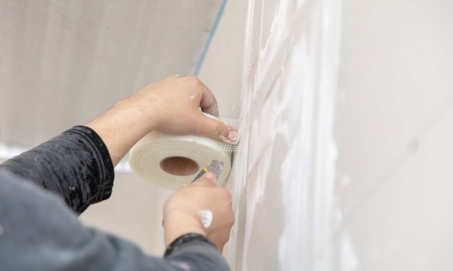 Person using drywall tape to repair drywall